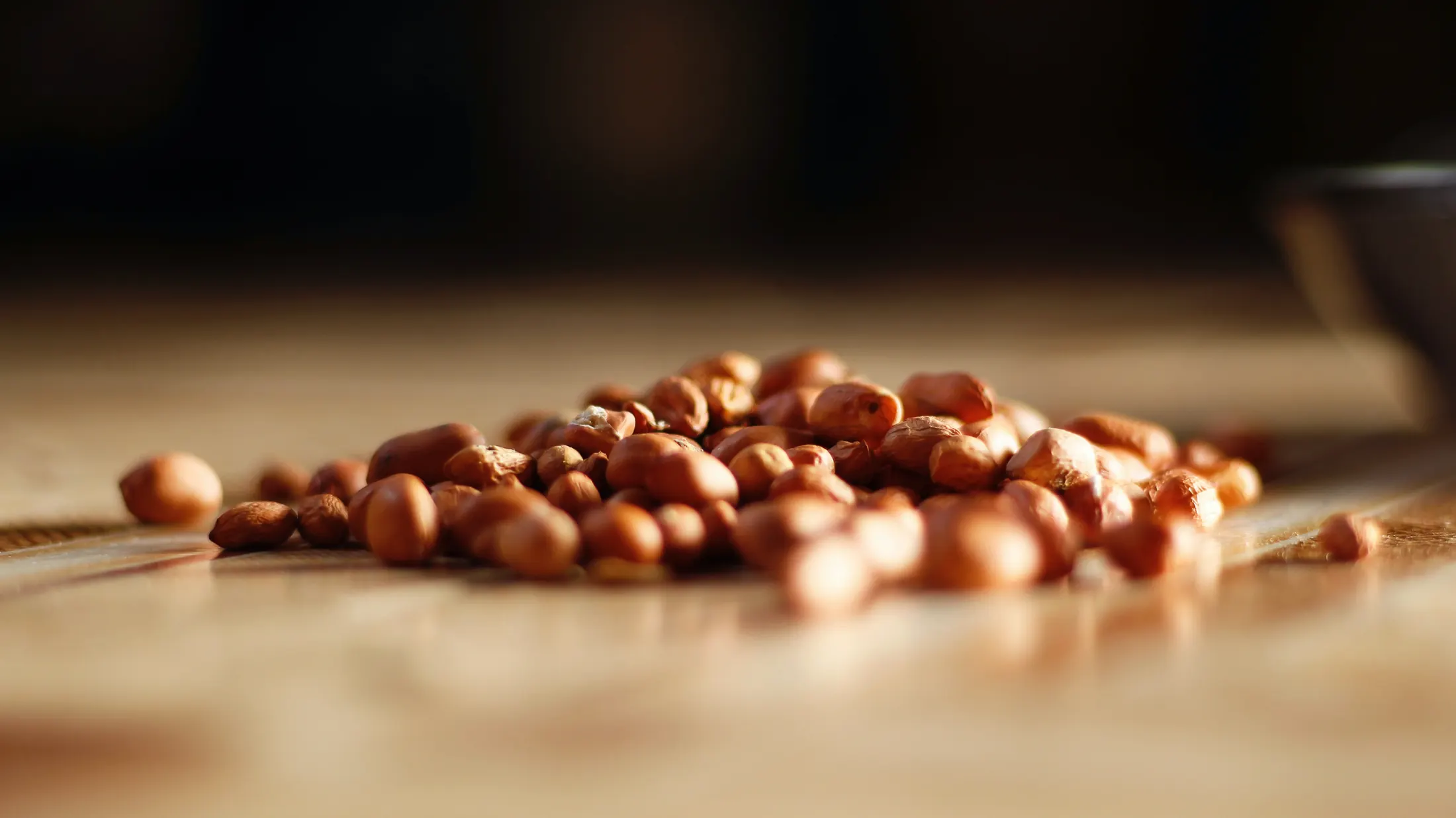 Red-skin peanuts spilled across a warm wooden surface